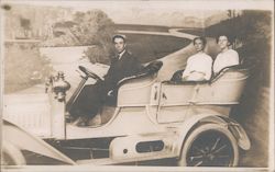 A Man and Two Women Sit in Car in Front of Backdrop in Photo Studio Postcard