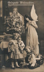 Gelegnete Weihnachten - angel looks over children with toys, Christmas tree in background Postcard