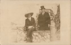 A Man Sitting on a Rock Wall and a Man Standing Behind Him Postcard