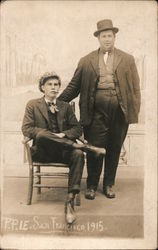 Two Men, One Standing Next to One in a Chair Postcard