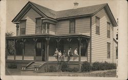 A Family Sitting on the Front Porch of a House Postcard