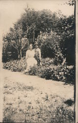 Woman and child posing in flower garden Postcard