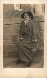 Woman in feathered hat posing on steps Postcard