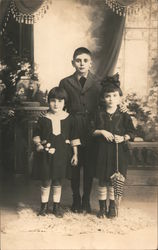 Three children dressed up, posing with flowers and parasol M. Camarrl Postcard Postcard Postcard