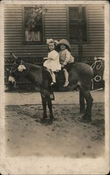 Young girl and boy riding donkey Postcard