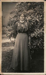 Older woman standing outside by bush Postcard