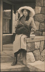 Woman posing on a stone porch rail. Postcard