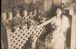 Woman poses with potted plants Postcard