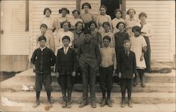 Children pose standing on the steps of a white building. Postcard