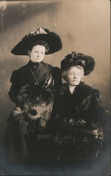 Two Women posing, in black hats and furs Postcard