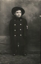 Young boy dressed in a dark hat and coat Postcard