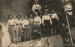 Group of men posing on boulder in front of waterfall Postcard