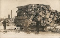 Three Men Standing By a Large Stack of Lumber Postcard