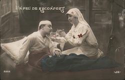 Red Cross nurse giving medicine by spoon to injured man at bedside. Postcard