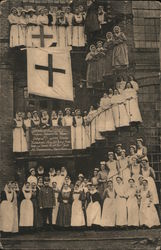 Red Cross nurses posed on outside building stairwells under large Red Cross Flag. Postcard Postcard Postcard