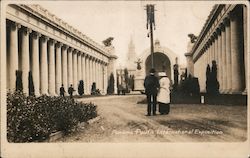 People walking on path through buildings with columns Postcard