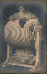 Surety Hose, Bowers Rubber Works. Woman standing next to large roll of hose on spindle Postcard