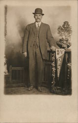 Studio photo of well dressed man with hat standing next to California banner, flowers Postcard Postcard Postcard