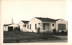 Couple standing outside their home, car in garage and in driveway Postcard