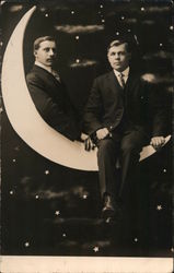 Photo of two young men sitting on a crescent paper moon Postcard