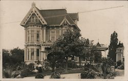 A woman standing in front of Victorian Home Postcard