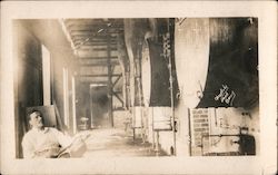 Man sitting among large vats Postcard