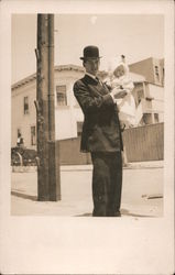 Man in bowler hat holding a baby Postcard