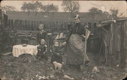 Woman and three children, outside, table set, well dressed, shack Postcard