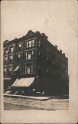 1800s Multistory Brick Building with Awning on Unpaved Street Postcard