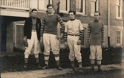 Four Football Players Standing in Front of Building 1920's Postcard