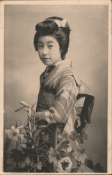 Young woman stands in kimono. She has a butterfly in her hair and is holding liles. Black and White photo. Asian Postcard Postca Postcard